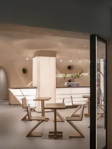Modern coffee shop with minimalist design featuring wooden tables and chairs.