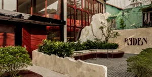 Modern restaurant exterior with concrete materials and greenery.