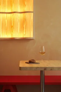 A wooden table with a wine glass and a pastry in a restaurant interior setting.