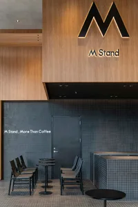 A well-designed modern coffee shop with wooden paneling on the walls, a black counter, and sleek black furniture.