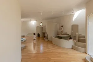 一間專為兒童設計的現代遊戲室，採用中性色調、平滑表面與木質地板。