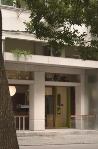 A modern commercial interior with concrete walls, glass doors, and green plants.