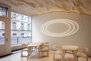 Modern cafe interior designed with wooden furniture and circular light fixtures.
