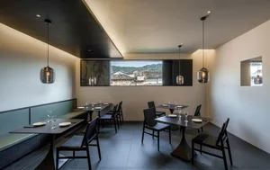 Modern restaurant interior with metallic pendant lights and concrete floor.