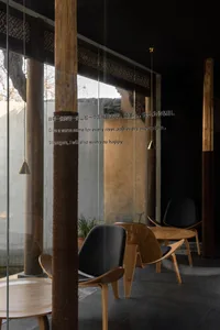 Modern restaurant interior with wooden furniture, black chairs, and glass walls