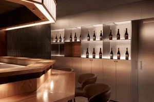 A modern bar interior featuring wooden fixtures, metal shelves, and glass bottles.