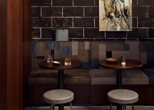 Industrial-themed cafe with dark walls, leather benches, and round tables.