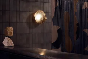 A modern industrial kitchen with metallic elements and a metallic sconce illuminated against a tiled wall.