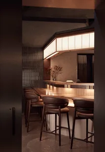 A modern bar counter space featuring wooden stools and a sleek, minimalist design.