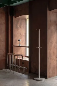 A minimalist coffee shop interior with wooden walls, bar stools, and a window.