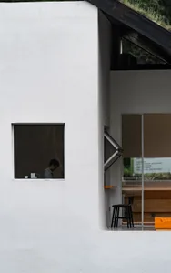 A minimalist white interior space with a window and seating area.