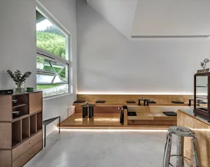 Modern cafe with minimalist design featuring wood materials and a seating area with windows