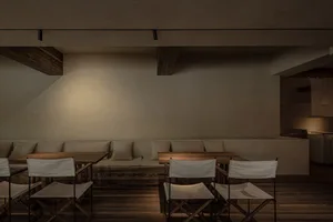Industrial-style restaurant interior featuring wooden tables and cushioned seating.
