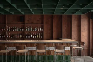 Modern bar interior with dark wood finishes, green and brown tile accents, and a variety of liquor bottles on the shelves.