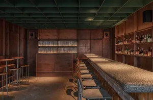 A minimalist bar with wooden countertops and stone finishes, featuring metal stools and shelves.