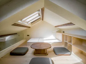 A modern living room featuring a wooden floor and furniture, with a skylight allowing natural light to enter the space.
