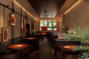 Modern restaurant interior with wooden tables and chairs, featuring a minimalist design aesthetic.