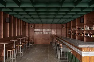 Concrete and wood interior of an industrial-style bar with high stools and shelves.