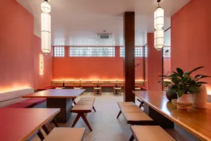Cafe interior with wooden furniture, red walls, and modern lighting.