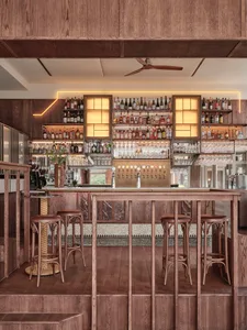 Modern interior of a cafe-bar with wooden flooring, marble accents, and metal details.