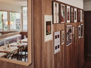 A modern restaurant interior with wooden paneling featuring a gallery wall of framed art.