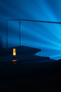 A minimalist lobby with blue lighting and a glowing yellow light