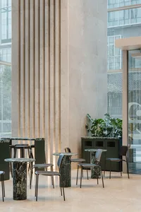 A modern coffee shop featuring marble and steel tables and chairs.