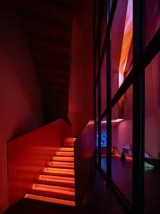 Modern interior design featuring a staircase with metal treads illuminated by red lights in a contemporary space.