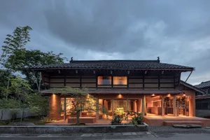 A modern house with a zinc roof and wooden terrace in a residential setting.
