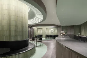 A modern restaurant interior with green tiles and concrete accents