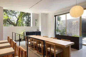 Modern restaurant interior with wooden furniture and large windows.