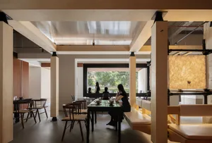 Interior of a modern restaurant featuring wood, concrete, and glass materials.