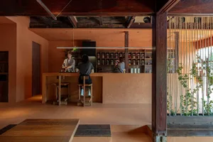 A rustic coffee shop interior with wooden materials, shelves filled with coffee-related items, and a barista working behind a