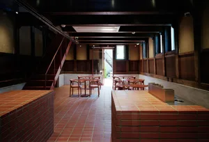 Modern cafe interior with brick walls, concrete flooring, and wooden furniture.