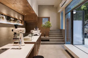 A coffee shop with a wooden counter and potted plants.