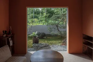 A serene modern interior featuring a gardenscape through a large window with stone, glass, and wooden elements.