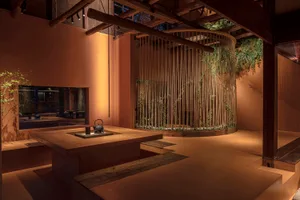 Industrial interior space with wood furniture, ceiling beams, and a central plant wall.