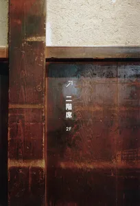 A wooden sign with Japanese text and an upward-pointing arrow.