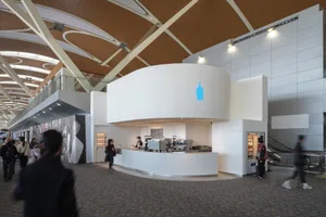 A modern airport food court with sleek white counters and contemporary lighting.