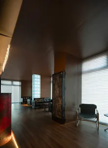 A modern office lounge with wooden flooring, leather sofas, and glass partition.