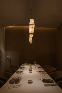 A modern restaurant dining room with wooden floors and hanging lights.