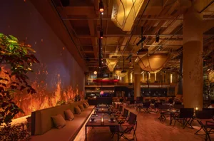 Industrial-themed restaurant interior with concrete walls, exposed steel, and glass elements.