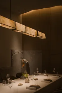 Modern, minimalist restaurant dining room with marble and concrete elements.