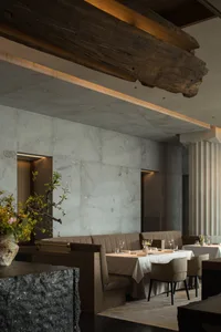Modern restaurant interior featuring minimalist design with concrete walls and seating arrangements.