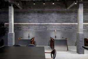 Modern restaurant interior with industrial design elements, featuring concrete, granite, and metal materials.