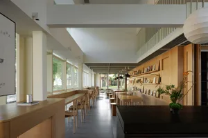 A spacious library cafe with wooden furniture, white walls, and large windows.
