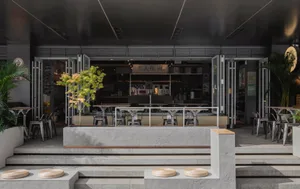 A minimalist coffee shop with a concrete exterior, featuring an open-air seating area and a modern design.