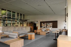 Modern lobby featuring wooden furniture and grey seating areas.
