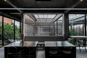 A minimalist office space with concrete walls, tables, and chairs.