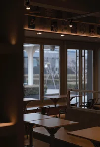 Indoor restaurant interior with wooden tables and chairs, industrial design elements, and natural light.
